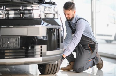 Modern araba tamirhanesinde arabalı dost canlısı bir tamirci. Profesyonel teknisyen araç kontrolü ve bakımını kontrol ediyor. Otomotiv endüstrisi ve müşteri hizmetleri kavramı.