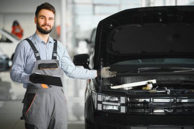 Auto mechanic holding clipboard checklist the car at mechanic shop, Mockup blank clipboard, Technician doing the checklist for repair machine a car in the garage clipart