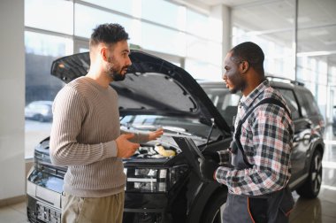 Tamirci çalışma sonucu adam. İstemci bir makinist araba tamiri değerlendirir.