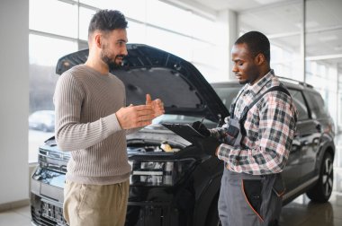 Tamirci çalışma sonucu adam. İstemci bir makinist araba tamiri değerlendirir.