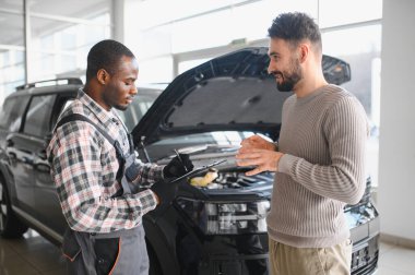 Tamirci çalışma sonucu adam. İstemci bir makinist araba tamiri değerlendirir.