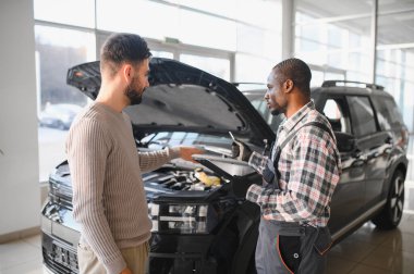 Tamirci çalışma sonucu adam. İstemci bir makinist araba tamiri değerlendirir.