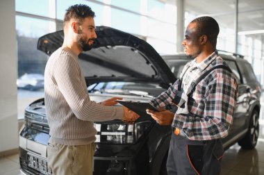 Tamirci çalışma sonucu adam. İstemci bir makinist araba tamiri değerlendirir.