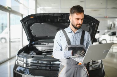 Otomotiv teknisyeni bilgisayarda tanılama yazılımı çalıştırıyor. Tamirci oto servis garajında araç tanılama testi yapıyor..