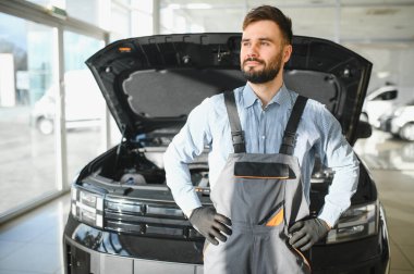 Araba tamircisi. Oto tamirhanesinde duran genç bir adam..