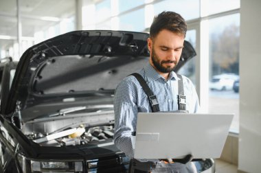 Tamirci Artırılmış Gerçeklik Tanılama Yazılımlı Bilgisayar Kullanıyor. Uzman Uzman Aracın Motorunu Kırık Parçaları Belirlemek İçin Denetliyor. Birinci sınıf araba servisi..