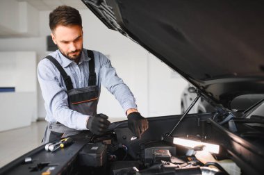 Modern araba tamirhanesinde arabalı dost canlısı bir tamirci. Profesyonel teknisyen araç kontrolü ve bakımını kontrol ediyor. Otomotiv endüstrisi ve müşteri hizmetleri kavramı.