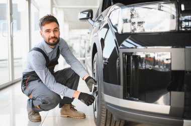 Modern araba tamirhanesinde arabalı dost canlısı bir tamirci. Profesyonel teknisyen araç kontrolü ve bakımını kontrol ediyor. Otomotiv endüstrisi ve müşteri hizmetleri kavramı.