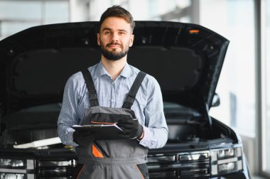 Auto mechanic holding clipboard checklist the car at mechanic shop, Mockup blank clipboard, Technician doing the checklist for repair machine a car in the garage