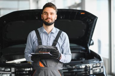 Auto mechanic holding clipboard checklist the car at mechanic shop, Mockup blank clipboard, Technician doing the checklist for repair machine a car in the garage clipart