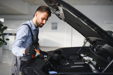 Modern araba tamirhanesinde arabalı dost canlısı bir tamirci. Profesyonel teknisyen araç kontrolü ve bakımını kontrol ediyor. Otomotiv endüstrisi ve müşteri hizmetleri kavramı.