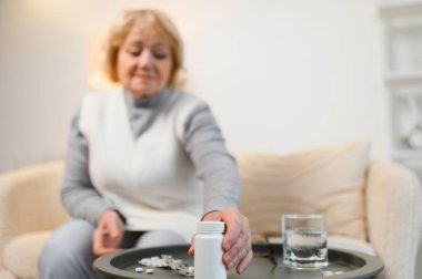Yaşlı kadın grip hastalığı sırasında elinde bir şişe hap tutuyordu. Haplara odaklan.