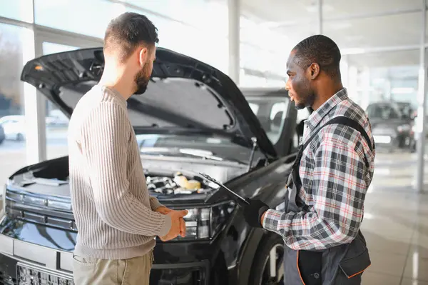 Tamirci çalışma sonucu adam. İstemci bir makinist araba tamiri değerlendirir.