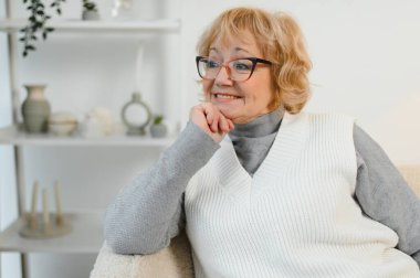 Rahatlatıcı yaşlı yaşlı kadın büyükannem oturma odasında kameraya bakıyor. Emeklilik konsepti.