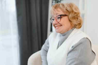 Rahatlatıcı yaşlı yaşlı kadın büyükannem oturma odasında kameraya bakıyor. Emeklilik konsepti.