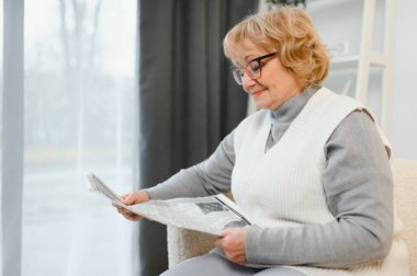 Yaşlı kadın dinleniyor ve gazete okuyor..