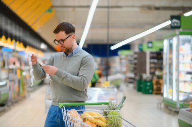 Kontrol ediyorum. Fiyatlar yüzünden hayal kırıklığına uğradım. Erkek müşteri süpermarkette..