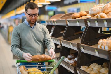 Genç adam süpermarketten alışveriş yapıyor. Tüketim kavramı.