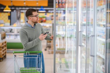 Genç adam süpermarketten alışveriş yapıyor. Tüketim kavramı.