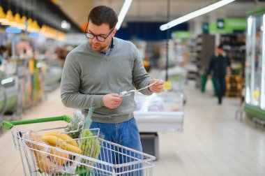 Şok olmuş bir adam marketteki mali faturaya bakıyor..