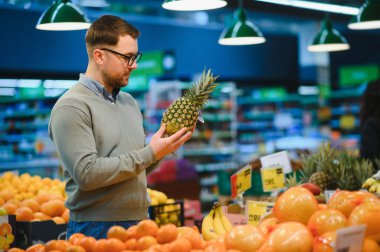 Genç adam süpermarketten alışveriş yapıyor. Tüketim kavramı.