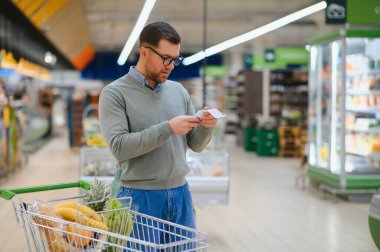Kontrol ediyorum. Fiyatlar yüzünden hayal kırıklığına uğradım. Erkek müşteri süpermarkette..