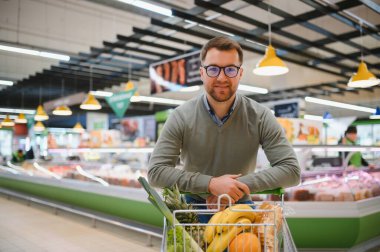Yakışıklı adam bir süpermarkette alışveriş.