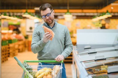 Donmuş balıklı sakallı adam elleri dondurulmuş gıda bölümündeki buzdolabının yanında duruyor..