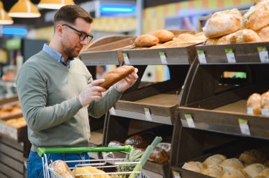 Genç adam süpermarketten alışveriş yapıyor. Tüketim kavramı.