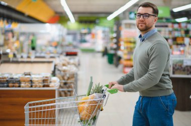 Yakışıklı adam bir süpermarkette alışveriş.