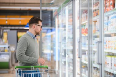 Yakışıklı adam bir süpermarkette alışveriş.