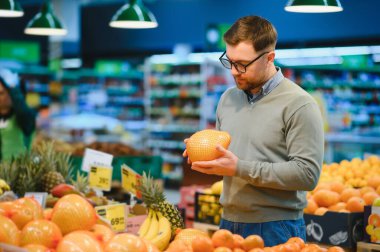 Genç adam süpermarketten alışveriş yapıyor. Tüketim kavramı.
