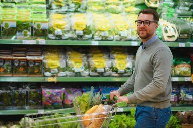 Yakışıklı adam bir süpermarkette alışveriş.