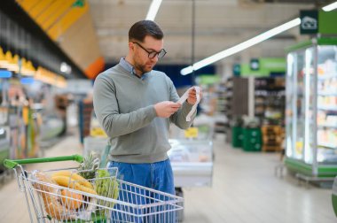 Yakışıklı adam bir süpermarkette alışveriş.