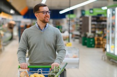 Genç adam süpermarketten alışveriş yapıyor. Tüketim kavramı.