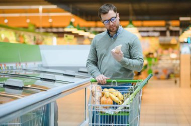 Yakışıklı adam bir süpermarkette alışveriş.