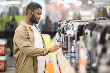 Alışveriş merkezinde kahve makinesini seçen adam..
