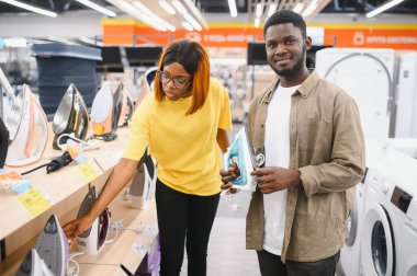 Elektronik mağazasında dikilen çift ütü yapmak için elektrikli ütü seçiyor. Ev işleri.