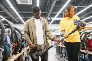 Genç ve güzel bir çift teknoloji mağazasından yeni elektrikli süpürge alıyor. Alışveriş yaparken eğleniyorum..