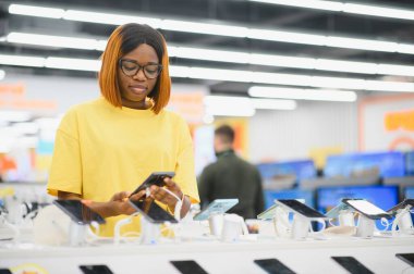 Kadın ev aletleri, elektronik aletler ve aletler mağazasından yeni akıllı telefon seçiyor..