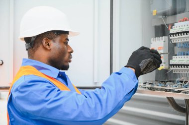 Neşeli Afrikalı Amerikalı elektrikçi dışarıda elektrik santrali kuruyor..