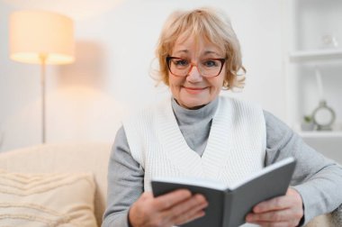 Huzurlu, olgun bir kadın kitap okuyor, favori edebiyat, son sınıf bayan dinleniyor, boş vakitlerin tadını çıkarıyor, hafta sonu evde..