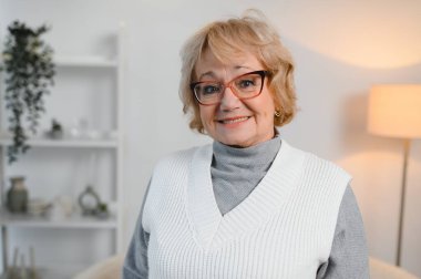 Evde dikilen mutlu son sınıf kadınının portresi. Neşeli emekli yaşlı bayan evde dinleniyor..