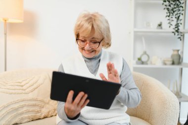 Yaşlı mutlu kadın ailesiyle bir tablette video görüşmesi yapıyor..