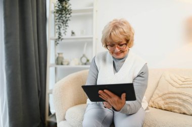 Yaşlı mutlu kadın ailesiyle bir tablette video görüşmesi yapıyor..