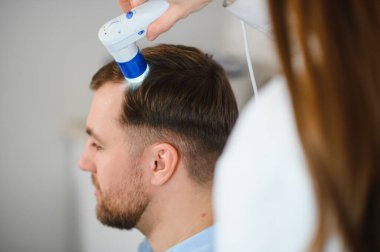 Bir tricholog, saç dökülmesine başlayan bir adamın saçını inceliyor. Bir dermatologla görüşeceğim. Saç dökülmesi, alopezi, pruritus, yanmakta olan kafa ya da sebora.