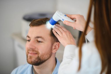 Bir tricholog, saç dökülmesine başlayan bir adamın saçını inceliyor. Bir dermatologla görüşeceğim. Saç dökülmesi, alopezi, pruritus, yanmakta olan kafa ya da sebora.