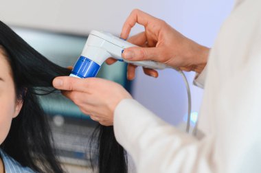 Bir dermatolog, genç bir kadına çekici bir hastanın saçının durumunu bilgisayarla teşhis eder. Trikoskopi, trikop, trikop, mikroskop..