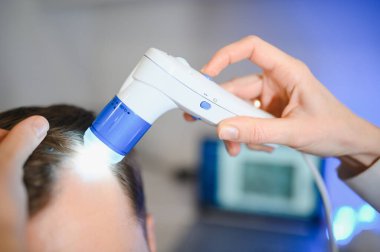 Bir tricholog, saç dökülmesine başlayan bir adamın saçını inceliyor. Bir dermatologla görüşeceğim. Saç dökülmesi, alopezi, pruritus, yanmakta olan kafa ya da sebora.