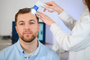 Bir tricholog, saç dökülmesine başlayan bir adamın saçını inceliyor. Bir dermatologla görüşeceğim. Saç dökülmesi, alopezi, pruritus, yanmakta olan kafa ya da sebora.